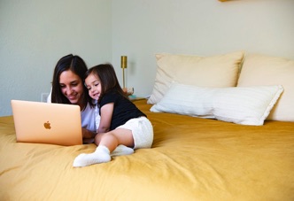 mother and child looking at a laptop on a bed